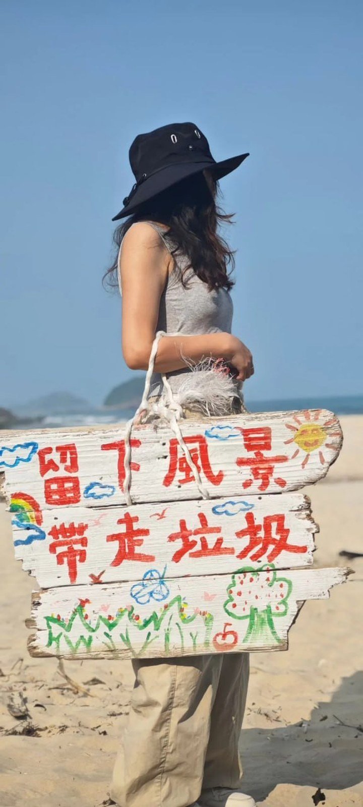 沐禾蒔光淨灘志工手持「留下風景 帶走垃圾」木牌